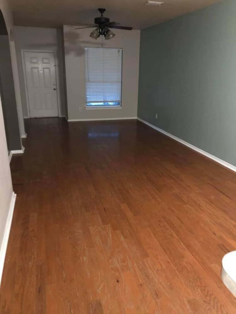 An empty living room with hardwood floors and a ceiling fan.