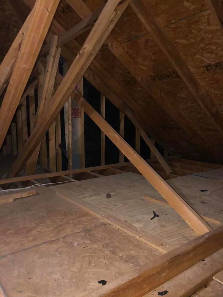 An attic with a lot of wooden beams and a wooden floor.