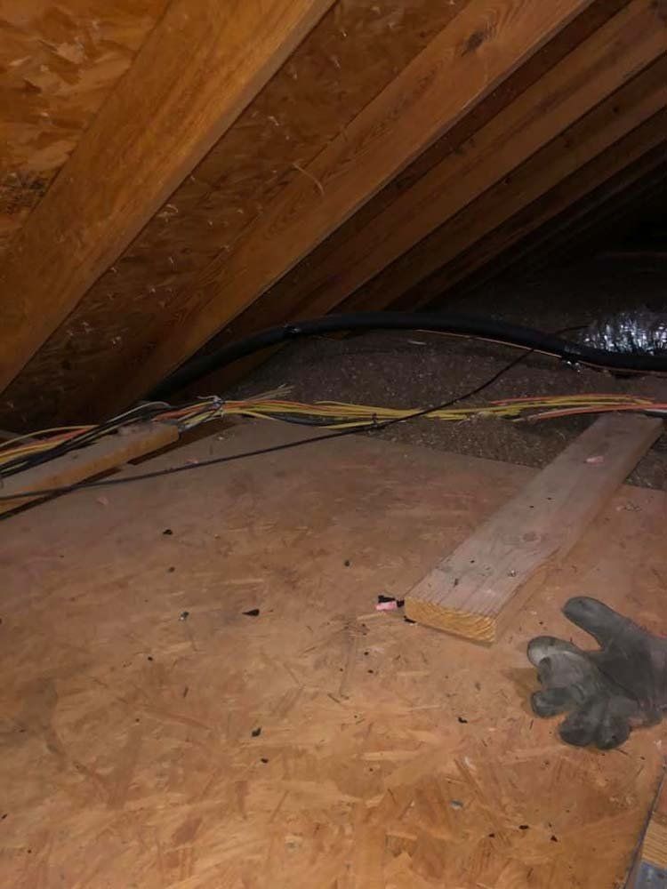 A person is holding a pair of gloves in an attic.
