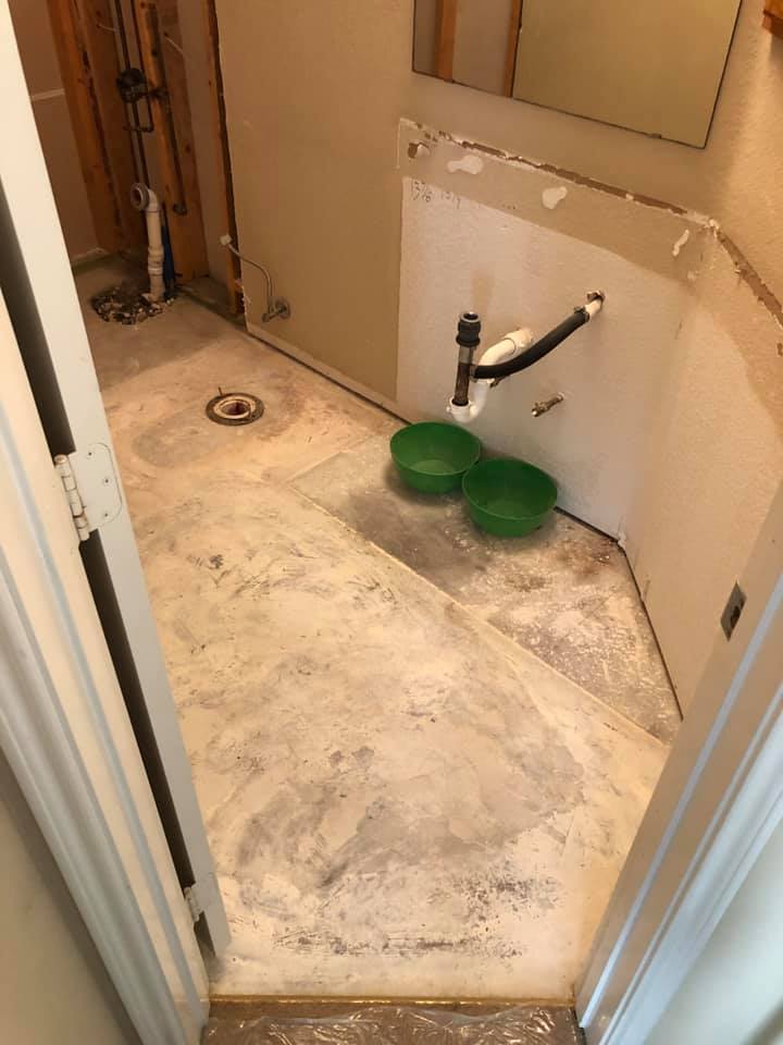 A bathroom with a sink and two green bowls on the floor.