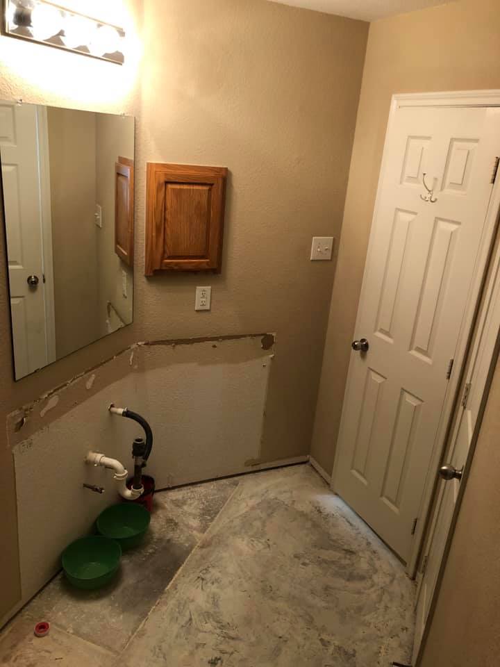 A bathroom with a sink , mirror , and door.