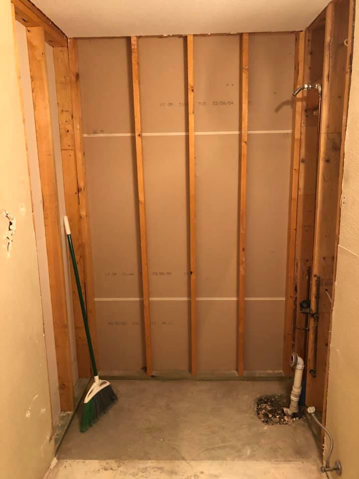 A bathroom under construction with a broom sitting on the floor.