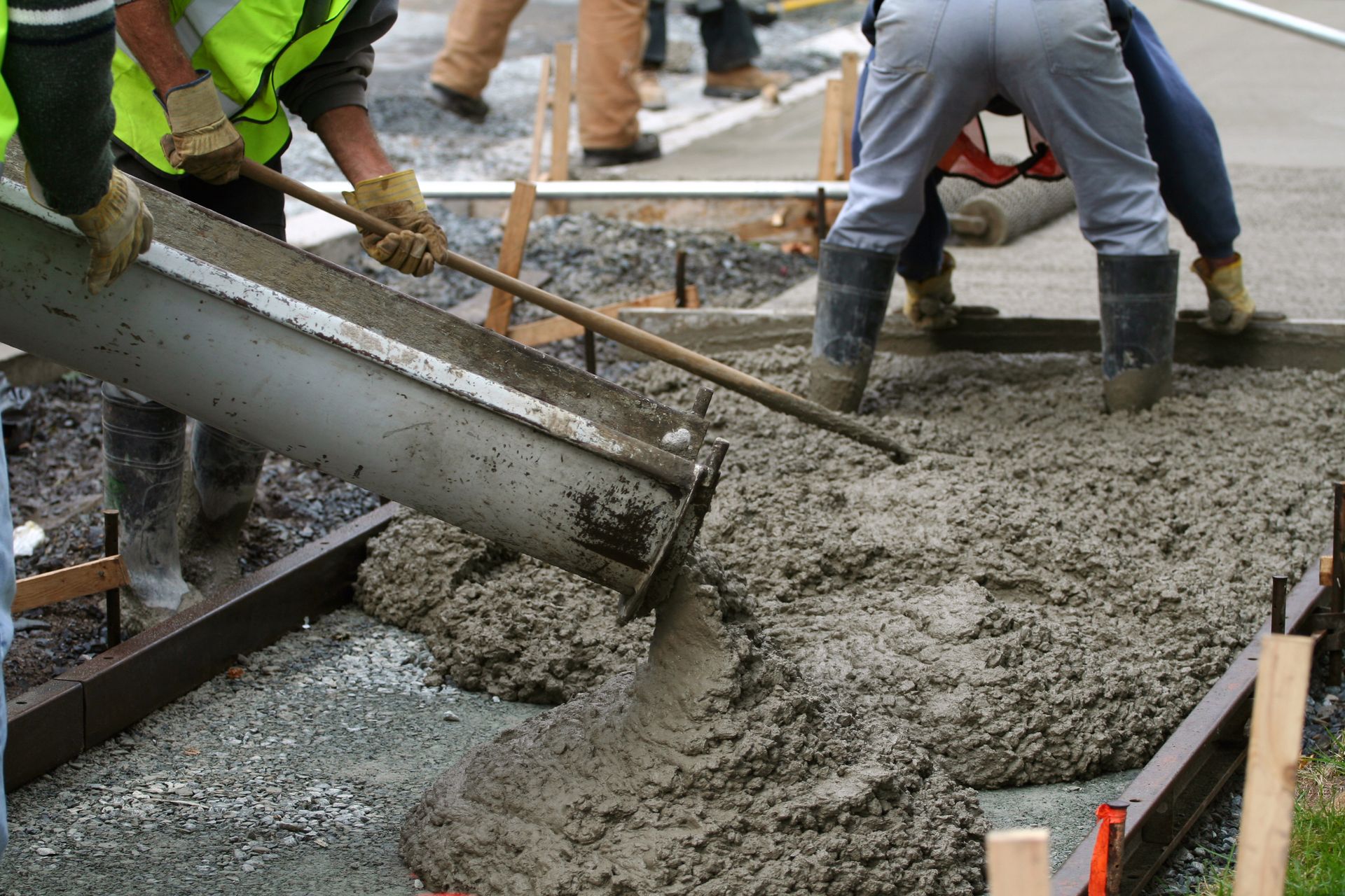 A group of construction workers are pouring concrete on a sidewalk