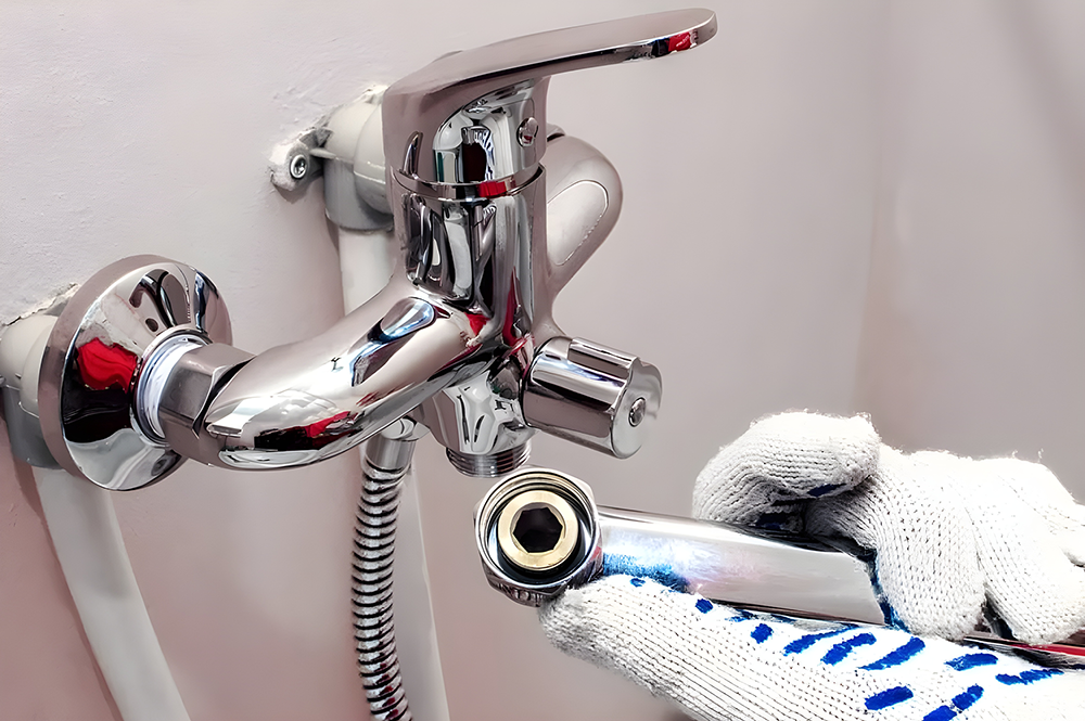 Gloved Hand Using Wrench On Faucet
