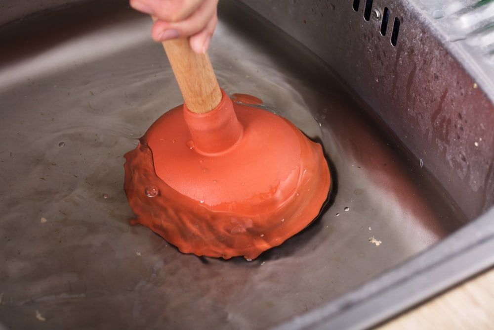 A person is using a plunger in a sink