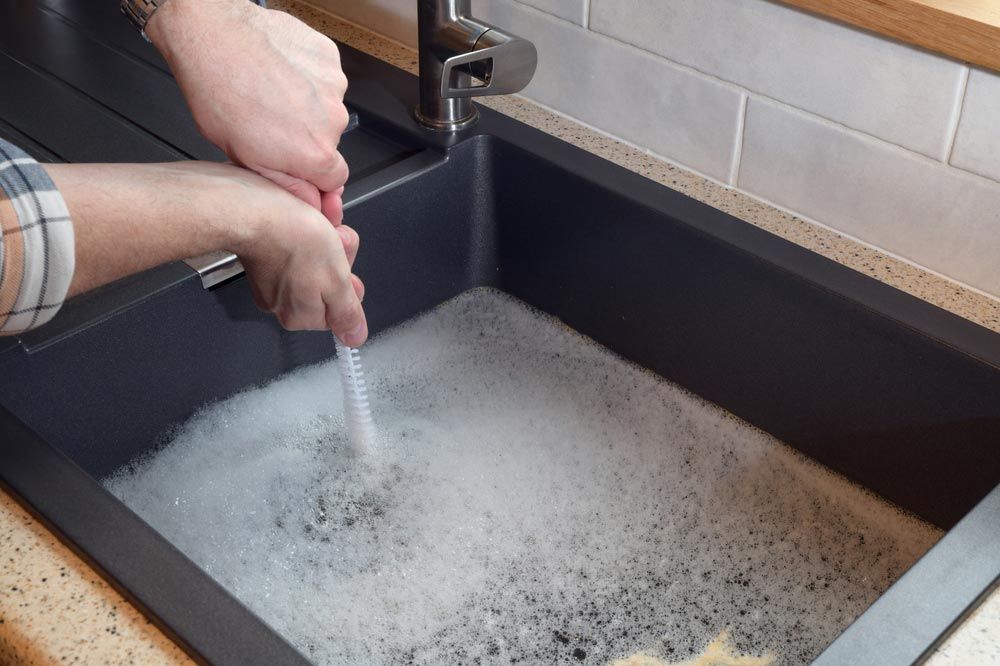 Man Trying To Fix A Blocked Kitchen Sink