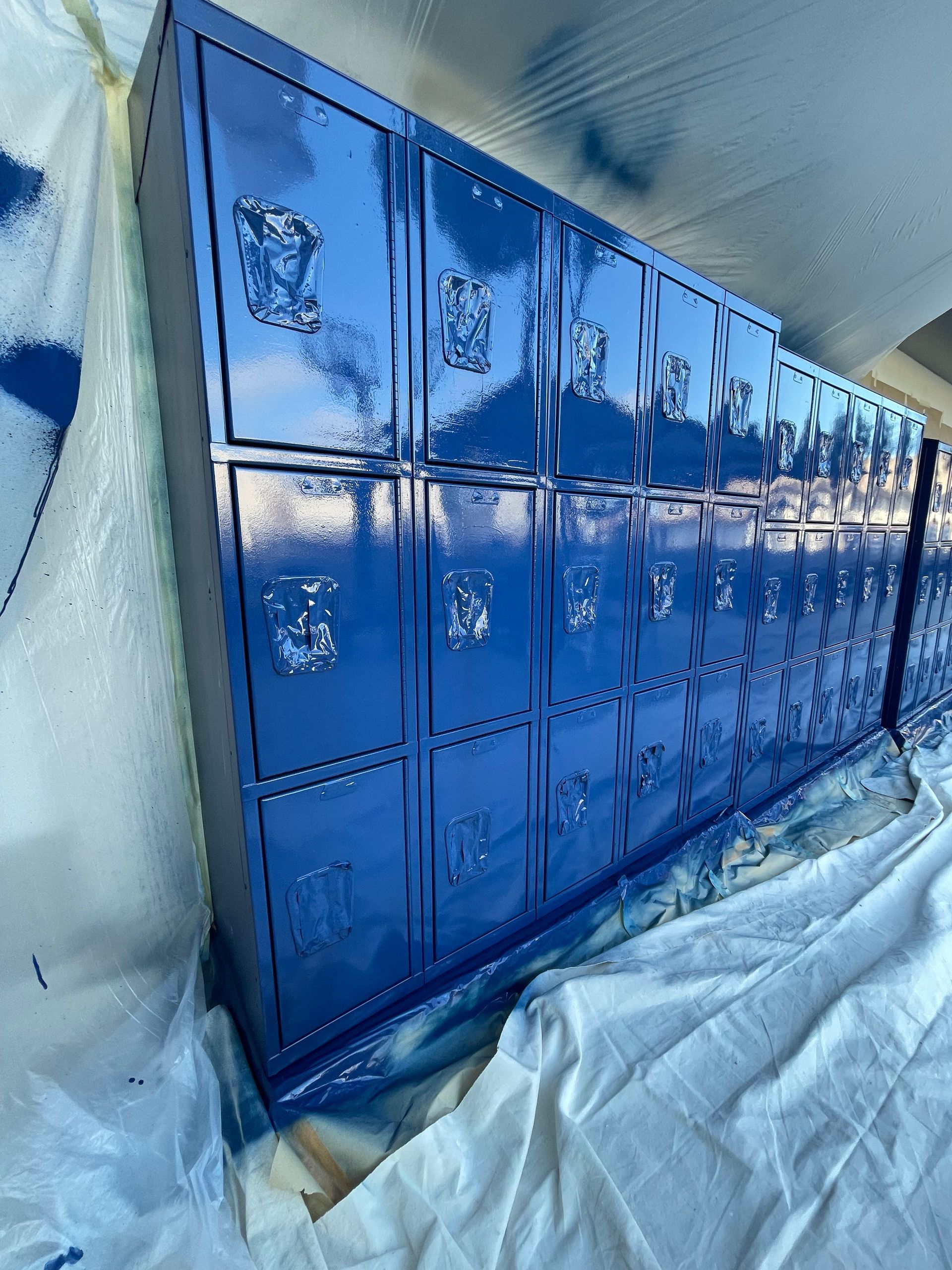 a row of blue lockers are being painted blue