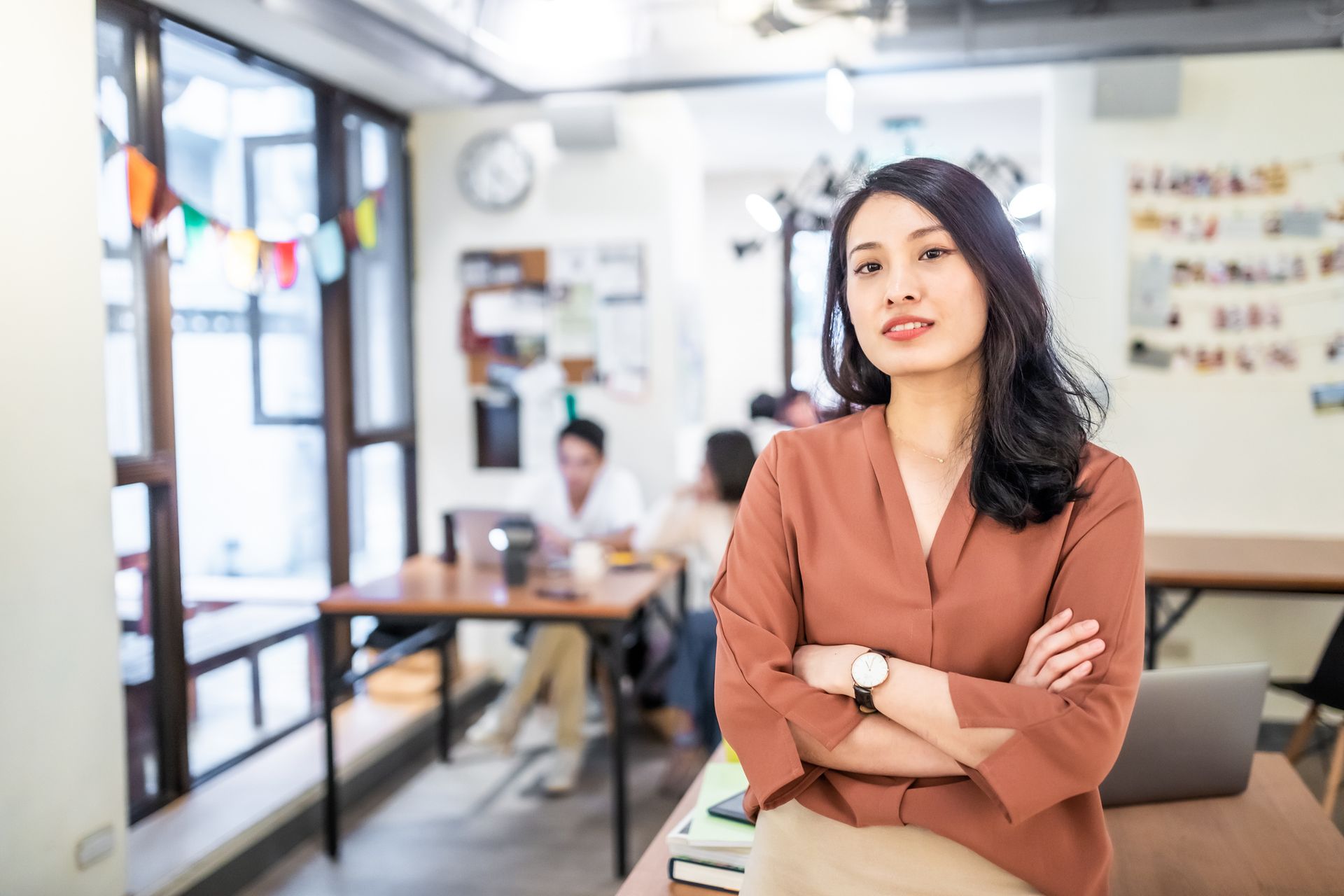 A woman is standing in an office with her arms crossed.