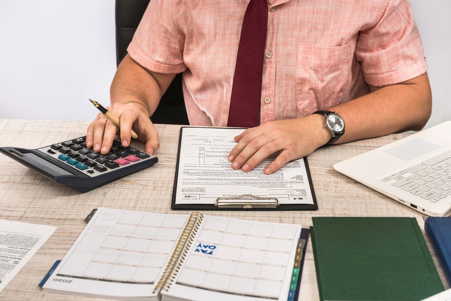 A man is sitting at a desk using a calculator.