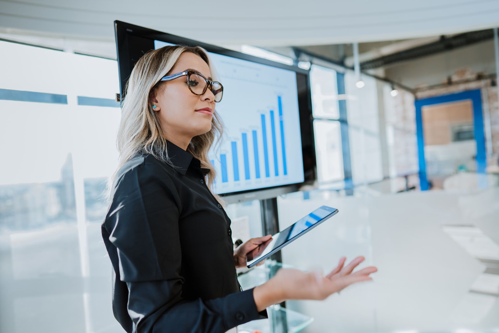 A woman is giving a presentation in front of a screen with a graph on it.