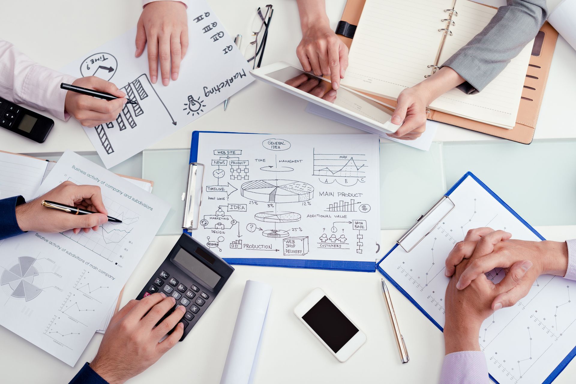 A group of people are sitting around a table with papers and a calculator.