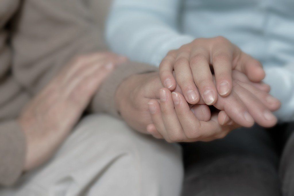 older couple holding hands, only hands are shown