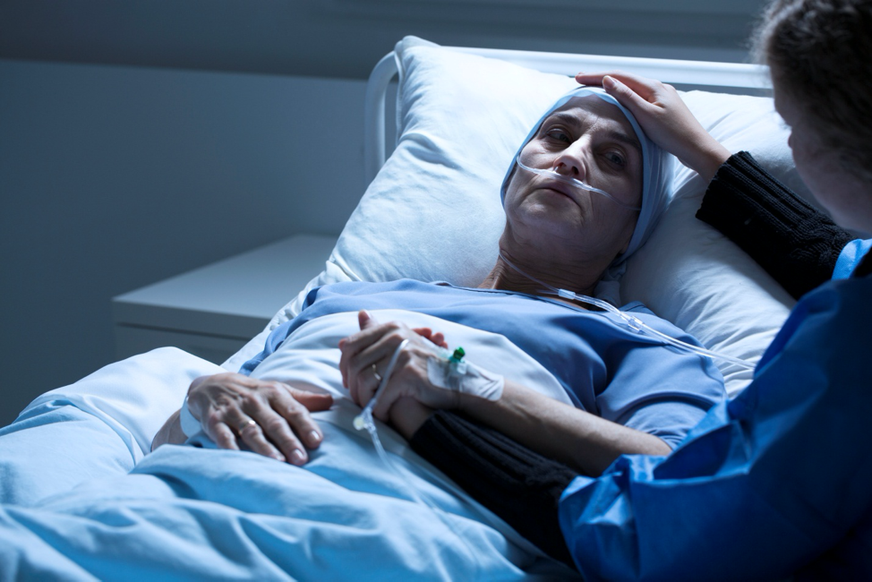 woman on deathbed looking at family member with worry on face