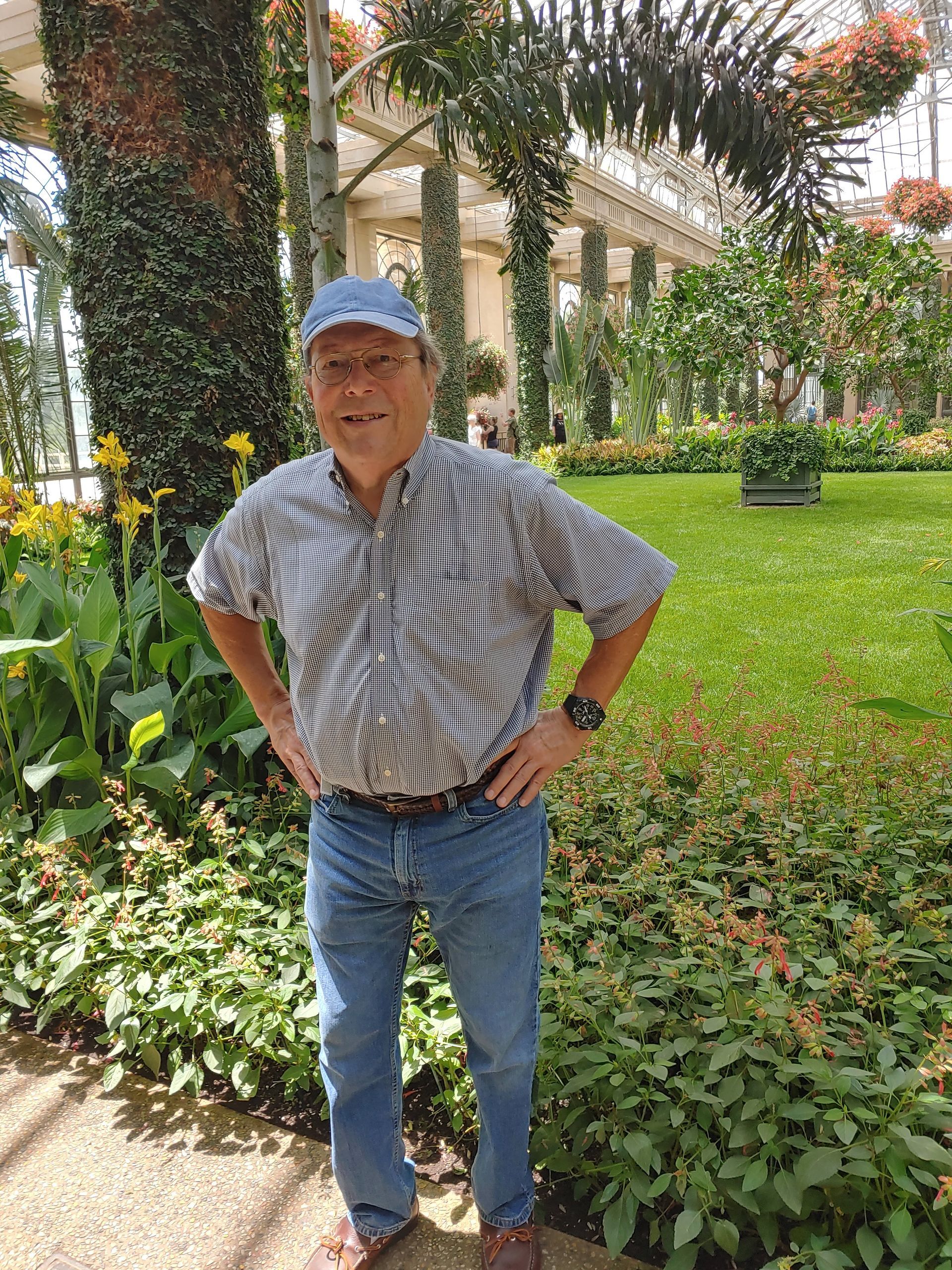 Man in blue shirt standing in front of a tree. 