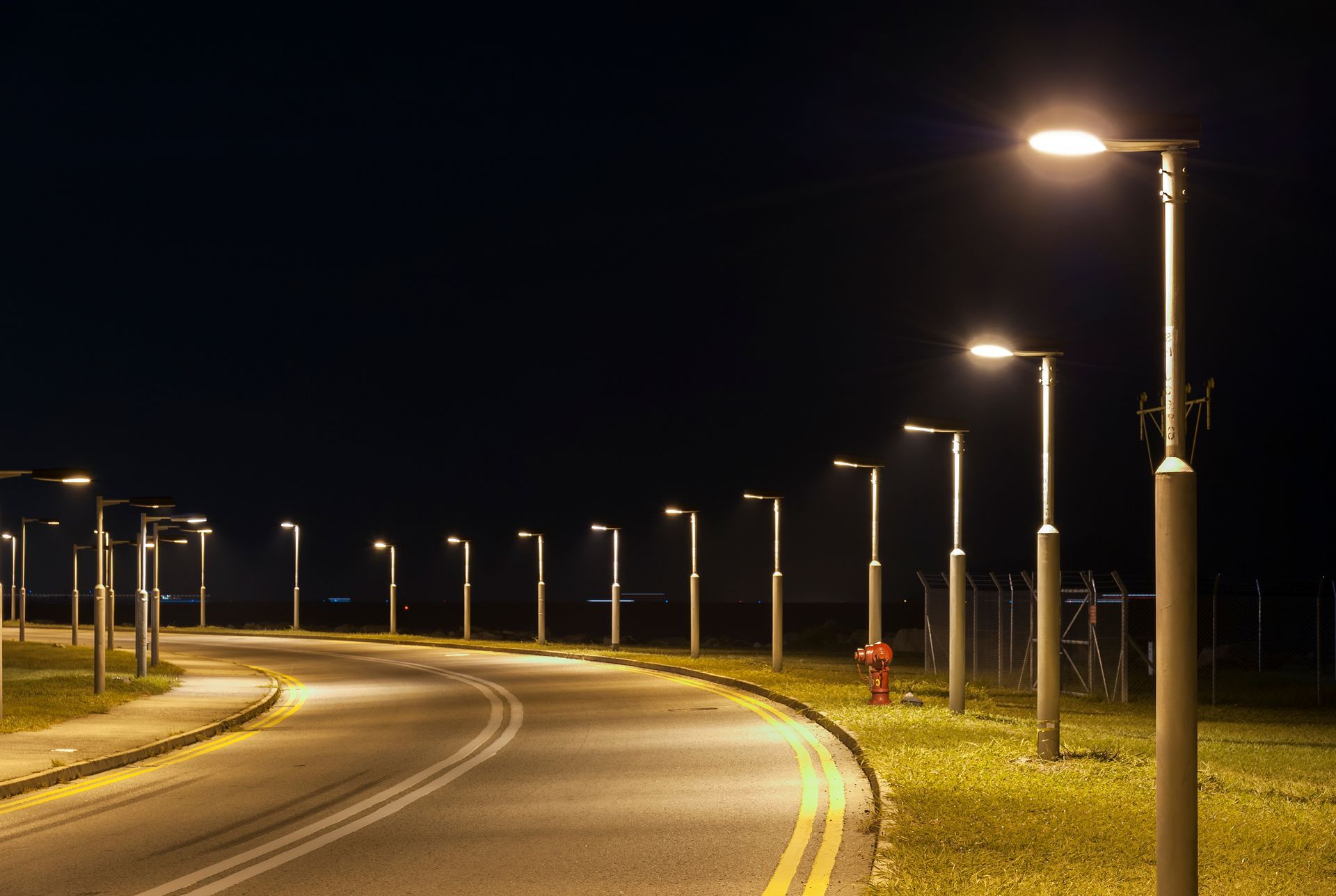 Curving road at night lit by a row of streetlights. Curving road at night lit by a row of streetlights.