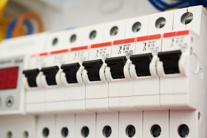 Close-up of a row of white electrical circuit breakers with black switches on a panel. Close-up of a row of white electrical circuit breakers with black switches on a panel.