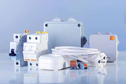 White electrical switches, outlets, and wiring accessories arranged on a reflective blue background. White electrical switches, outlets, and wiring accessories arranged on a reflective blue background.
