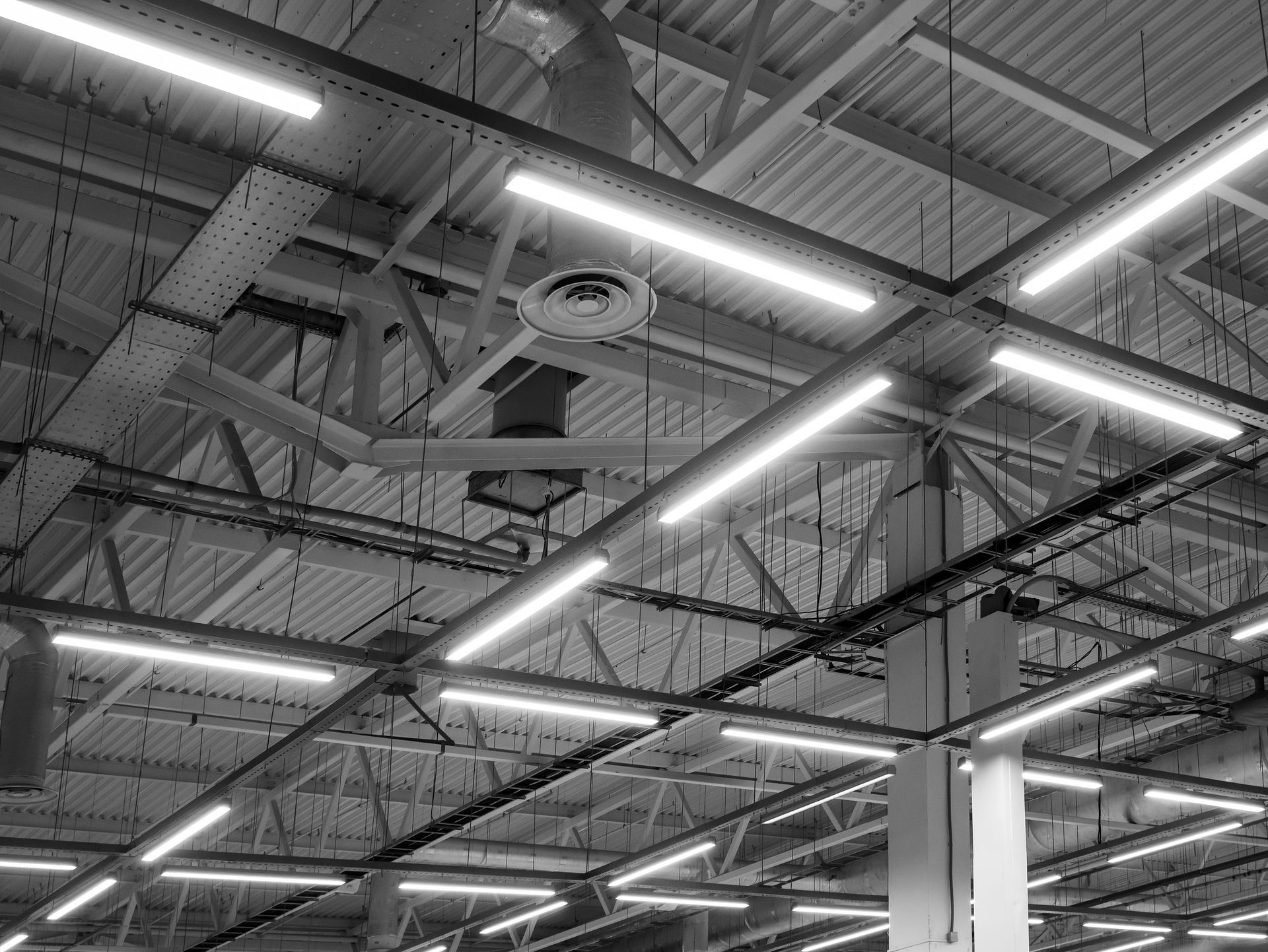 Ceiling of an industrial warehouse with exposed beams and bright fluorescent strip lights. Ceiling of an industrial warehouse with exposed beams and bright fluorescent strip lights.