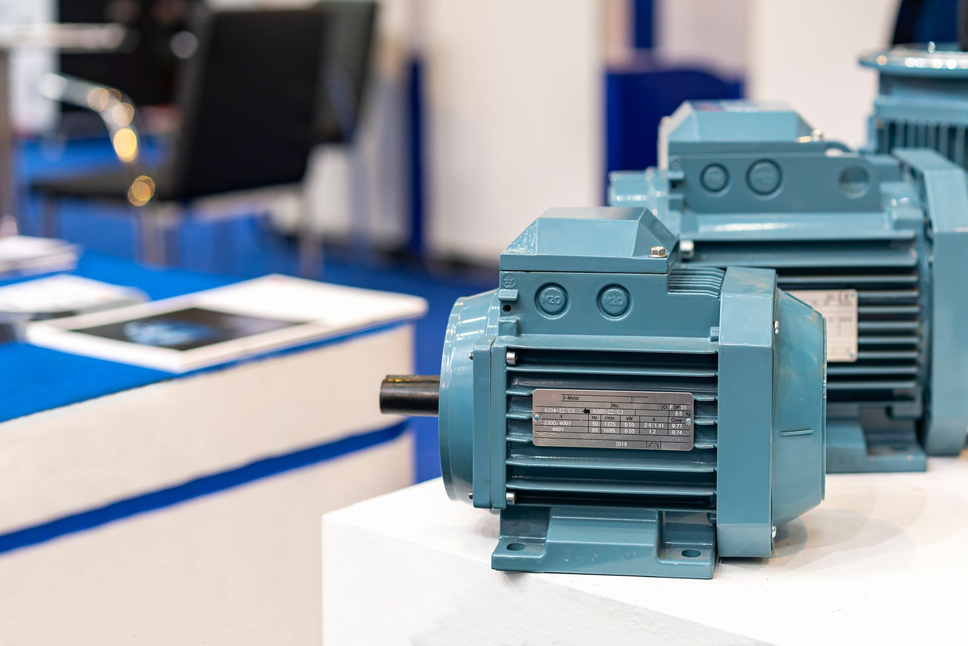 Teal electric motors displayed on a white table in a factory or showroom. Teal electric motors displayed on a white table in a factory or showroom.