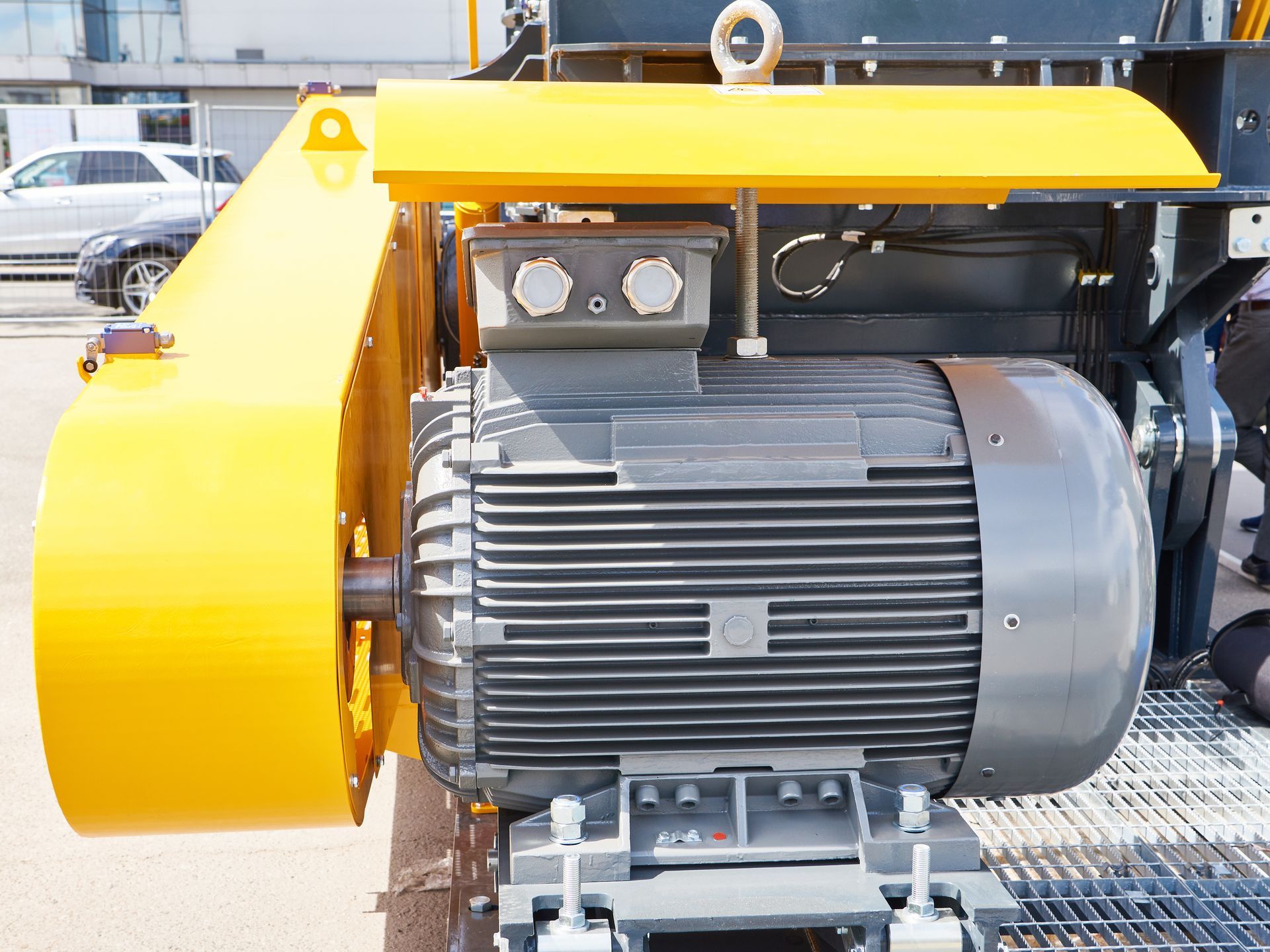Yellow industrial electric motor with protective housing on a metal platform outdoors. Yellow industrial electric motor with protective housing on a metal platform outdoors.