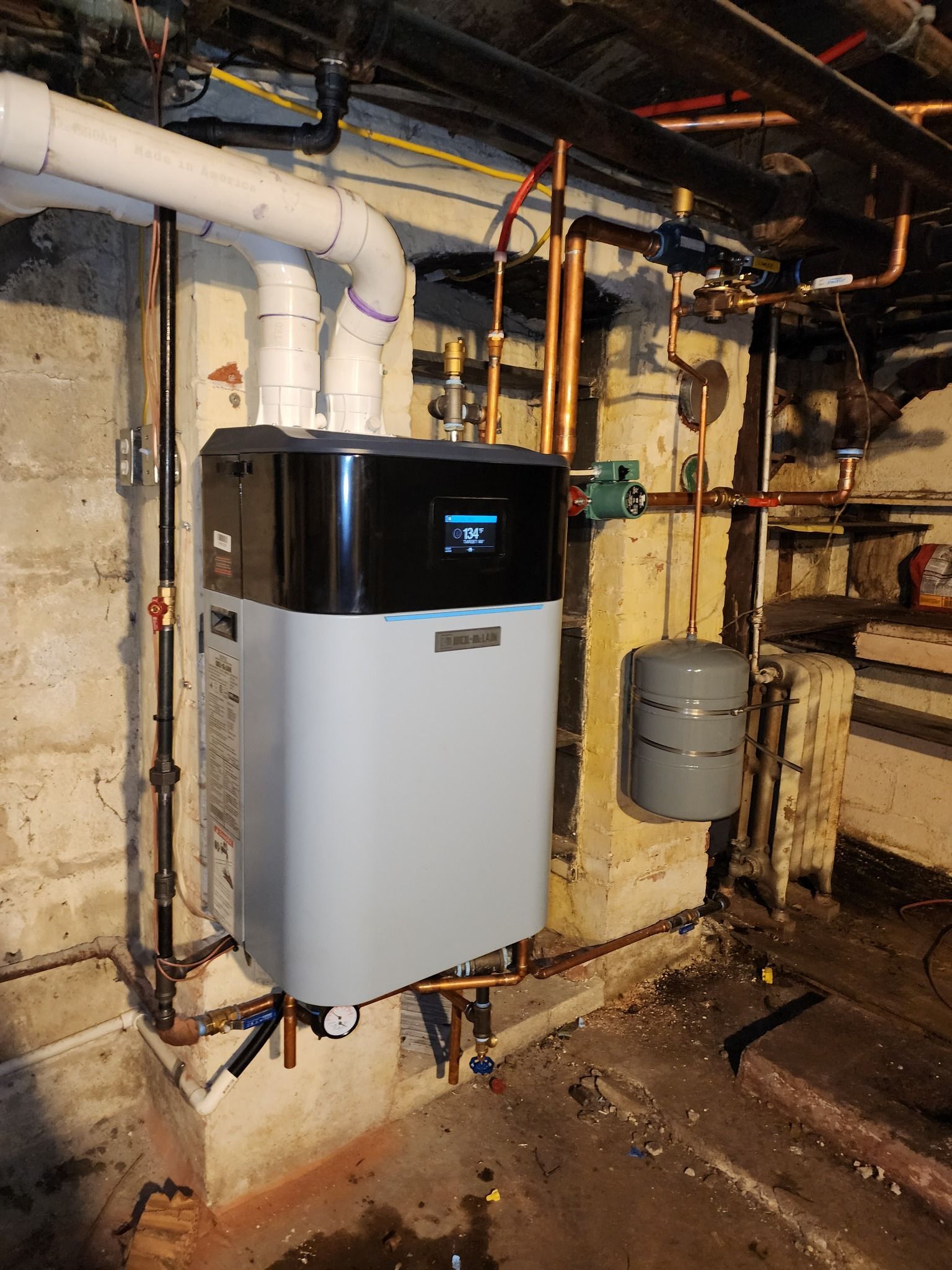 Kenders Heating And Air Conditioning | a water heater is hanging on a wall in a basement.