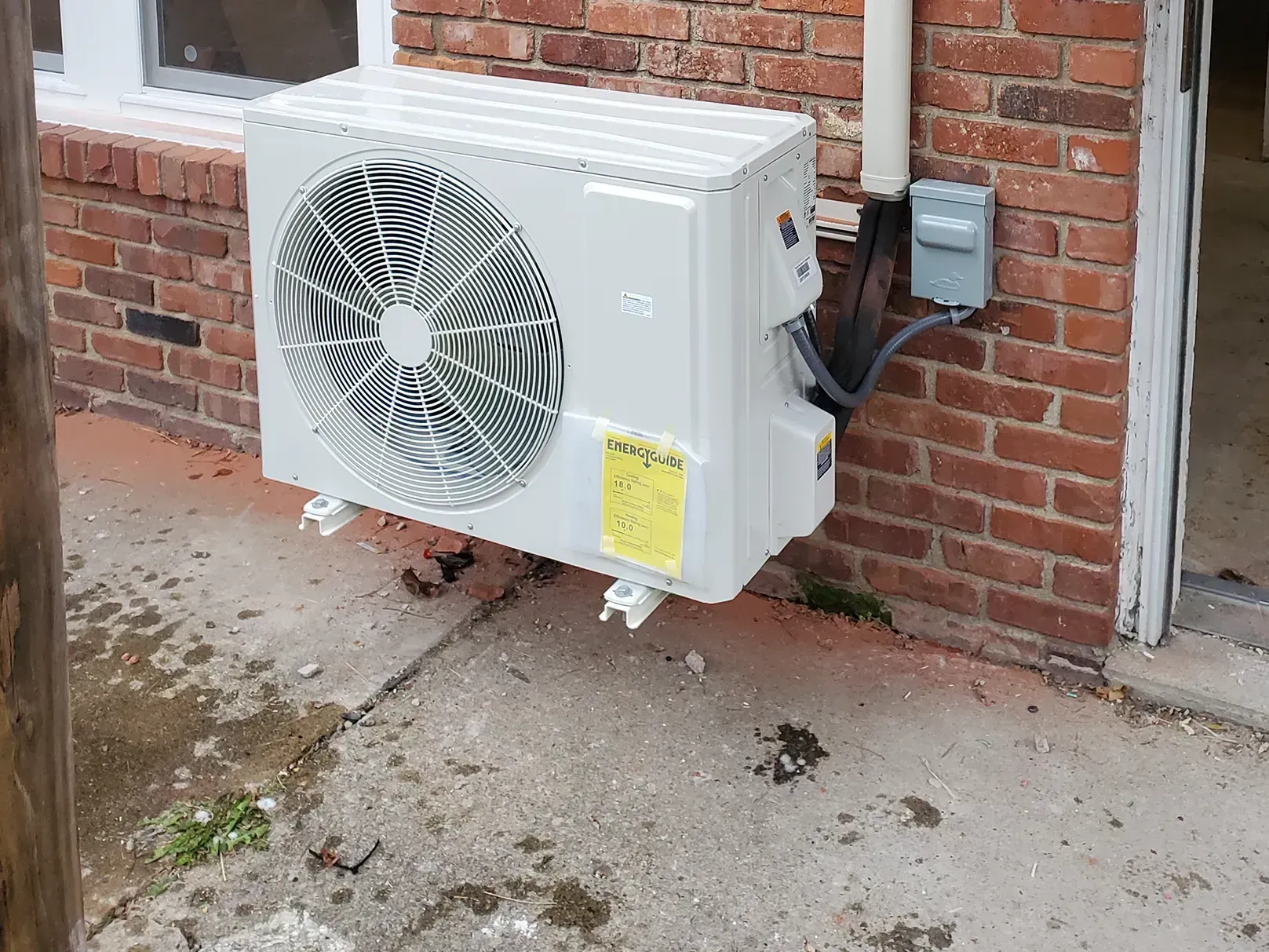 Kenders Heating And Air Conditioning | a white air conditioner is mounted on the side of a brick building.