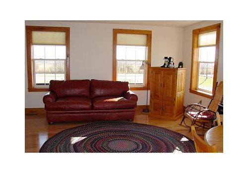 Living room with red sofa, round rug, wooden cabinet, and three sunlit windows