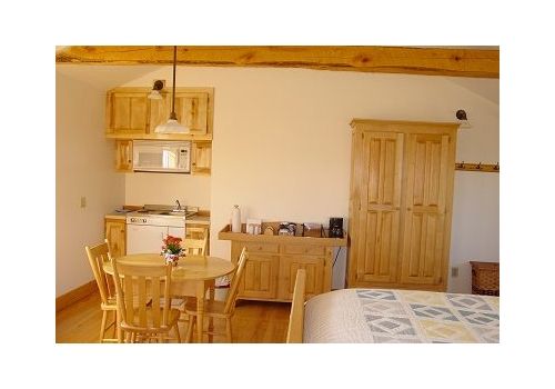Cozy wooden bedroom with dining table, cabinet, wardrobe, and bed under exposed beams