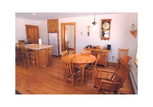 Wood-floored dining room with wooden tables, chairs, and a kitchen island