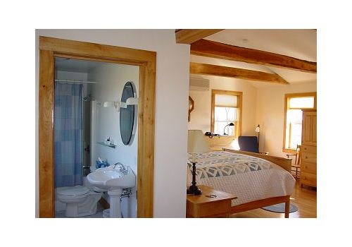 Bedroom and bathroom in a rustic room with wood beams and warm light