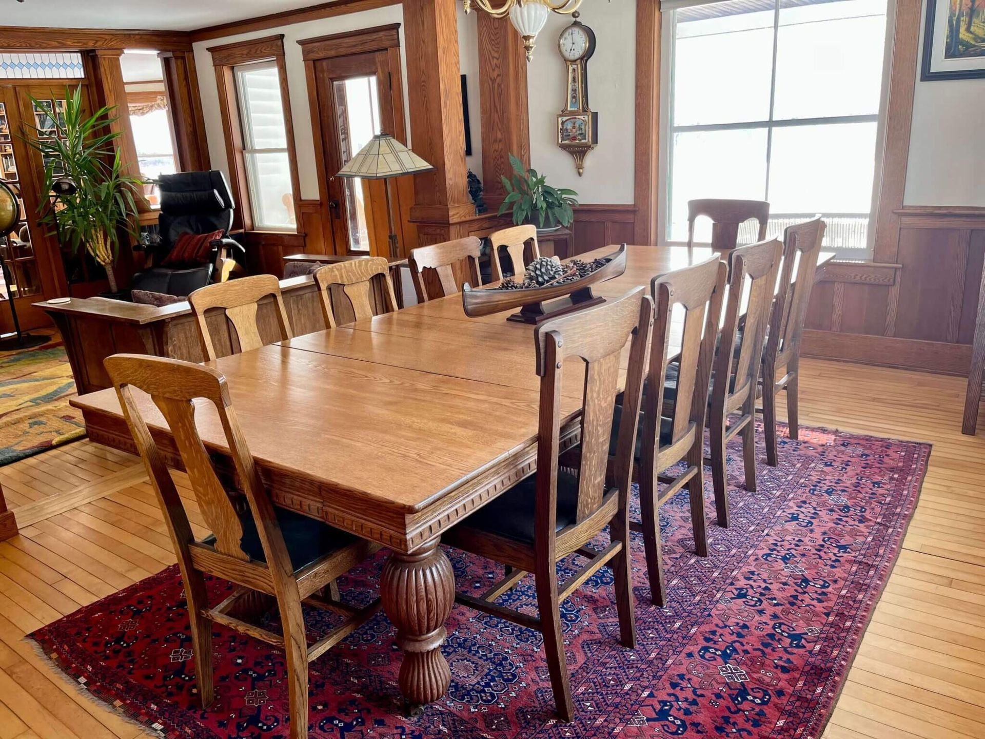Wooden dining table set for a meal, in a room with hardwood floors and a red rug.