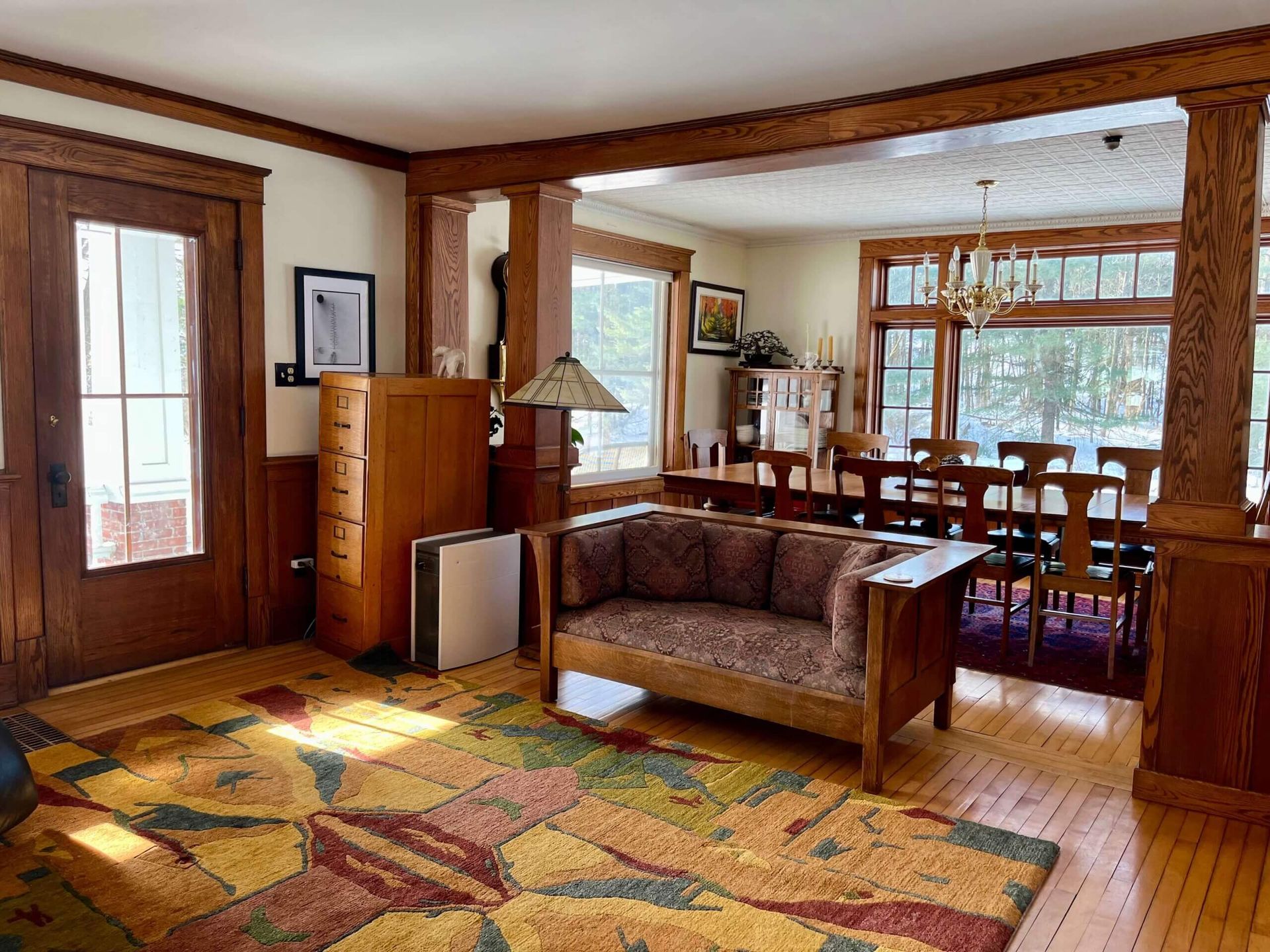 Living room with wood trim, colorful rug, sofa, and dining area visible in the background.
