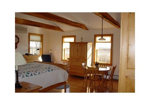 Cozy rustic bedroom with exposed beams, wooden furniture, and sunlight through windows