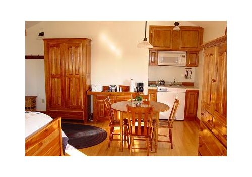 Warm kitchen with wooden cabinets, dining table, and white appliances in a bright interior.