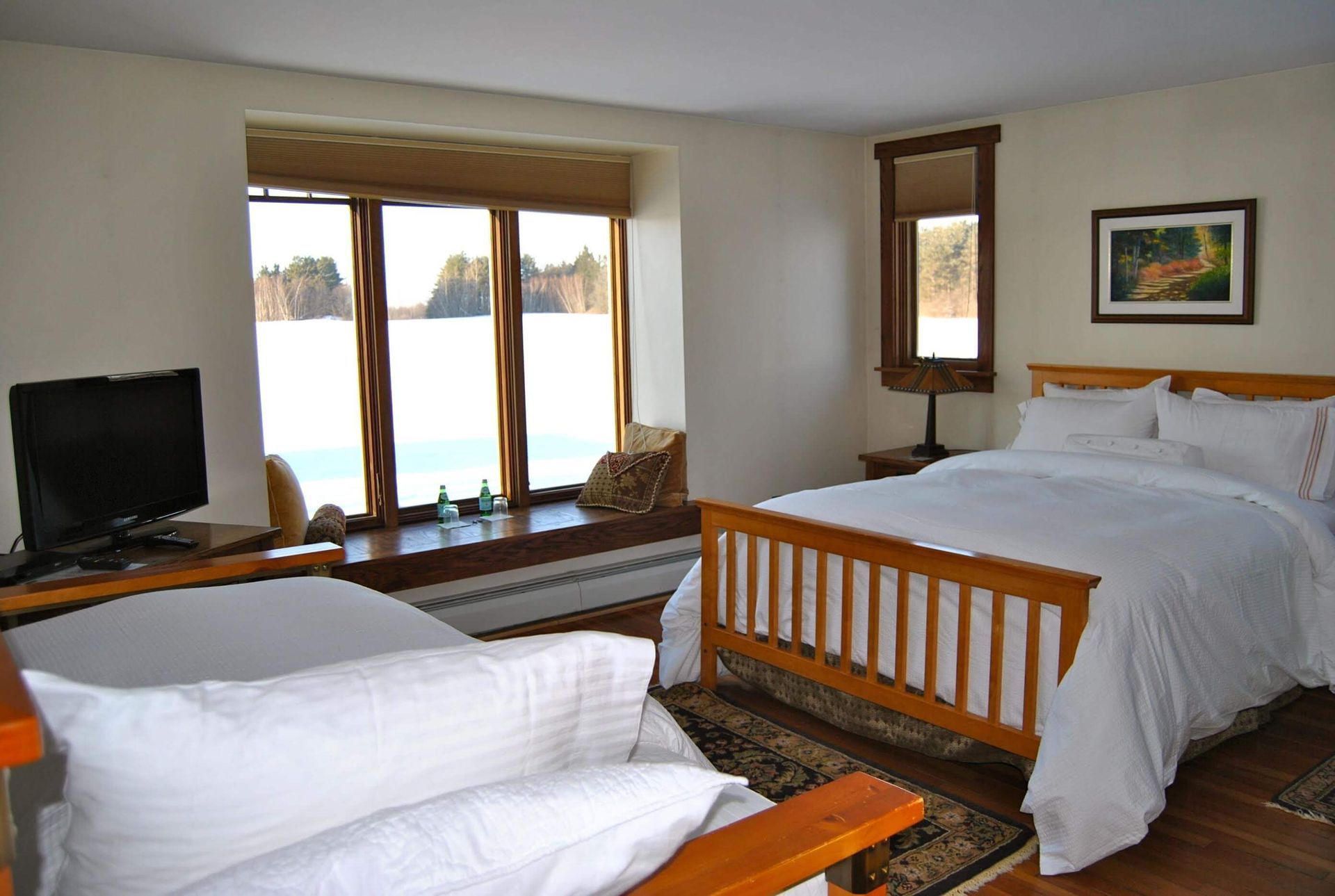 Bedroom with large window overlooking water, bed, seating area, and TV.