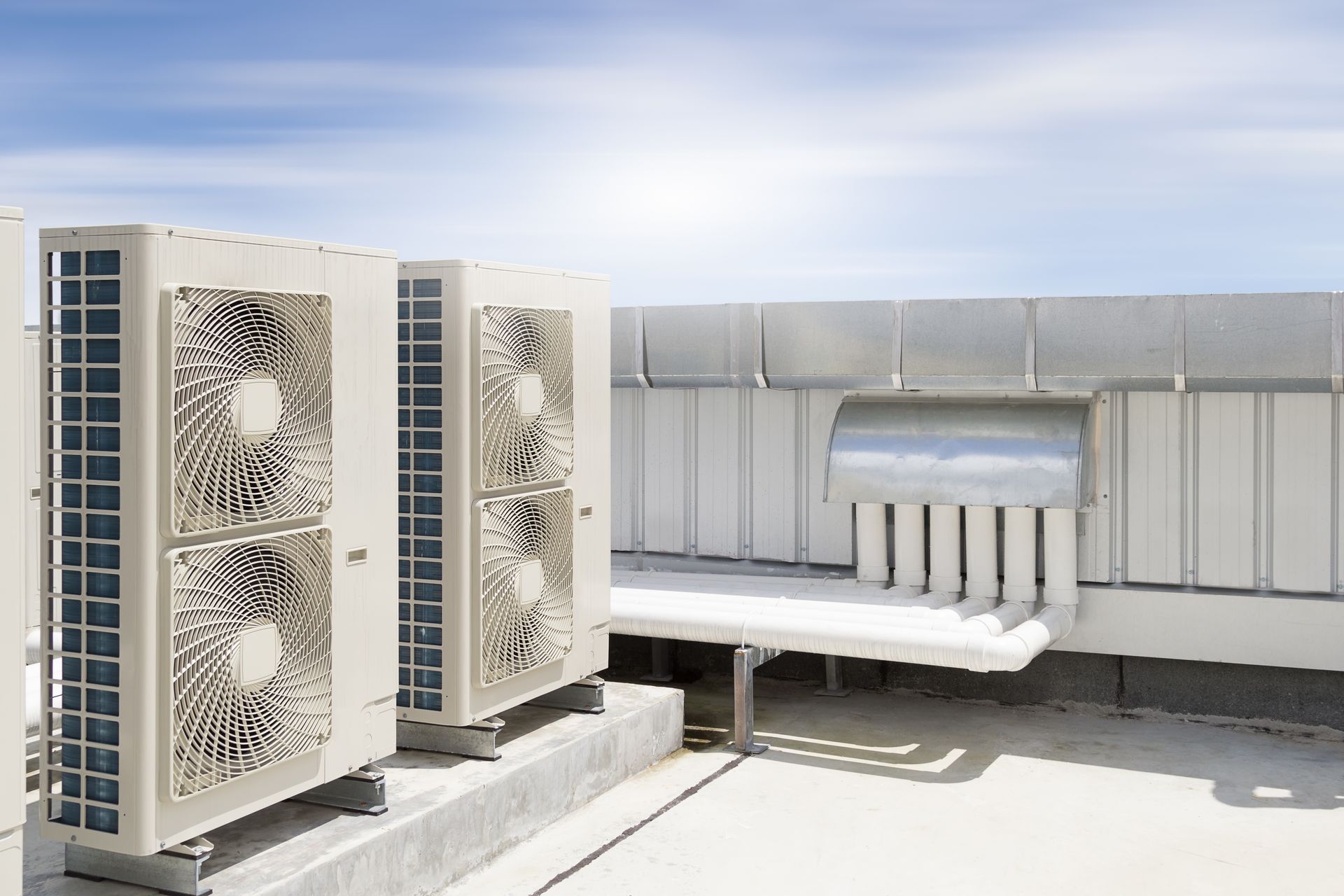 Air conditioning units on a building rooftop, with ventilation and pipes.