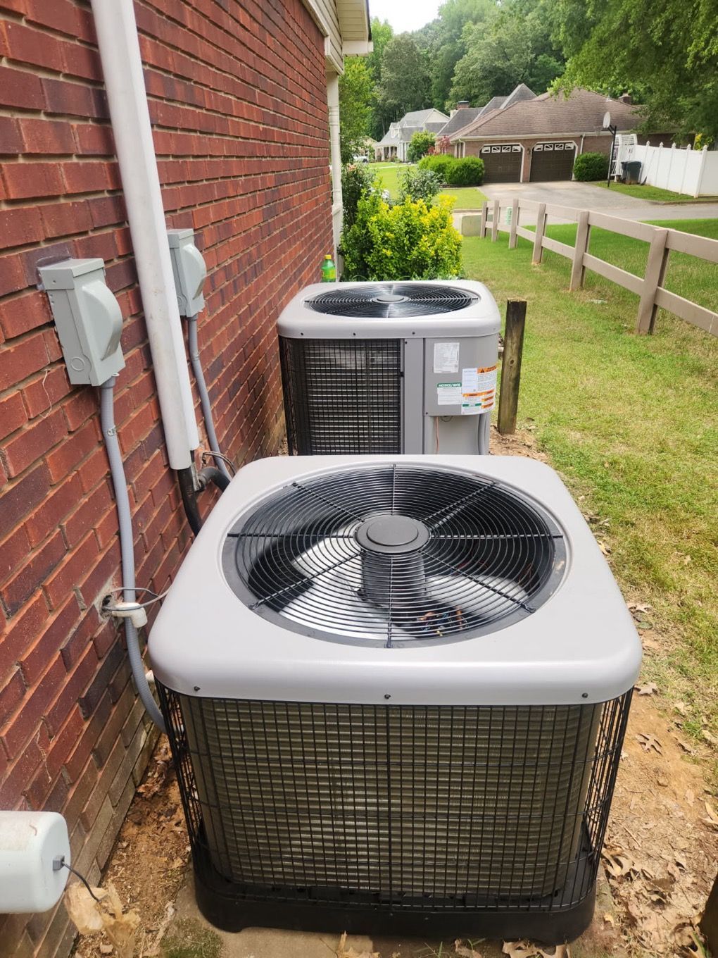 Gray HVAC unit with four fans outdoors near a building and grass.