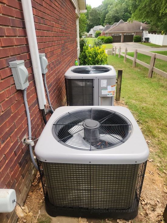 Gray HVAC unit with four fans outdoors near a building and grass.