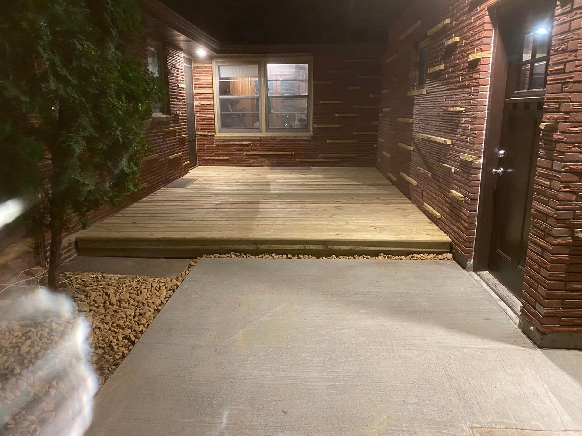 A wooden deck is sitting in front of a brick building at night.