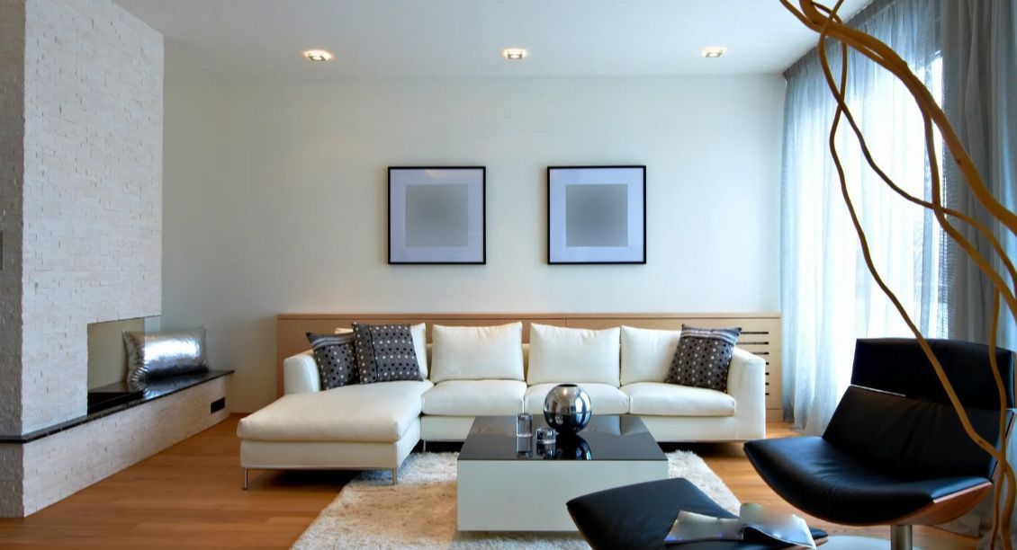 A living room with a white sectional couch and a black chair