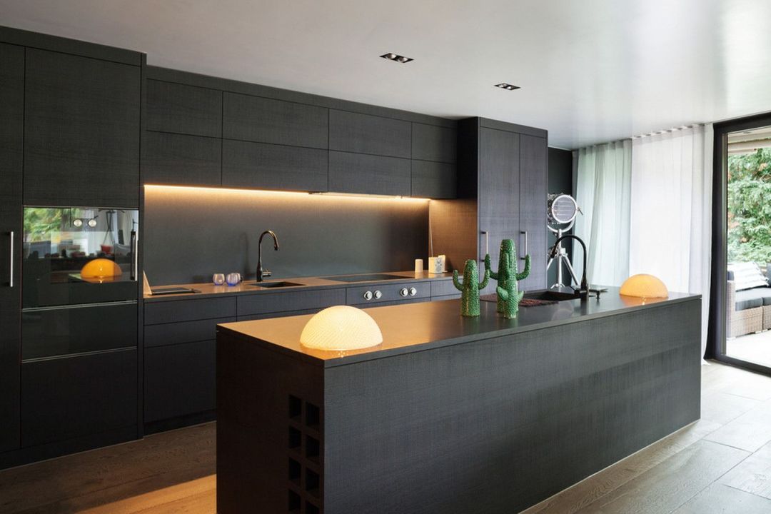 A kitchen with black cabinets and a large island in the middle.