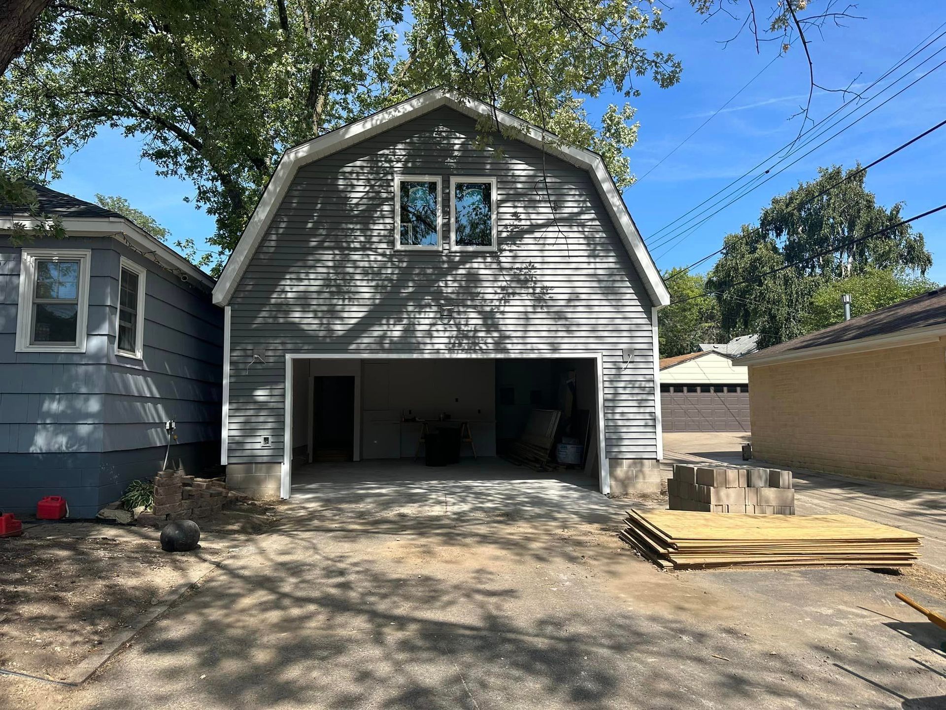 A barn shaped garage is being built next to a house.