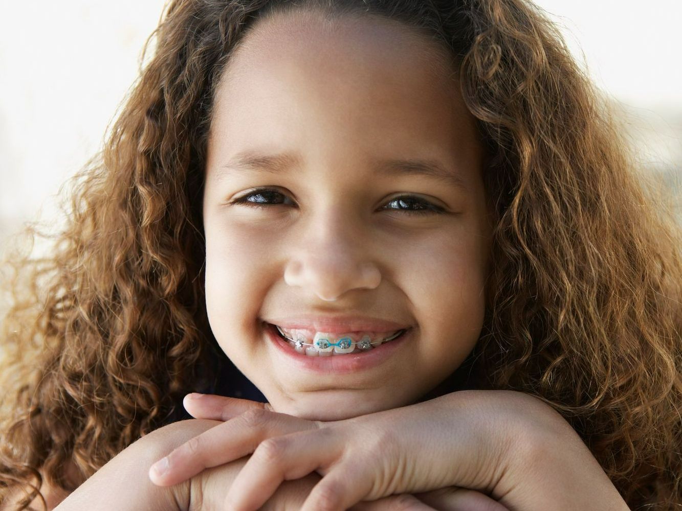 A young girl with braces on her teeth is smiling for the camera.