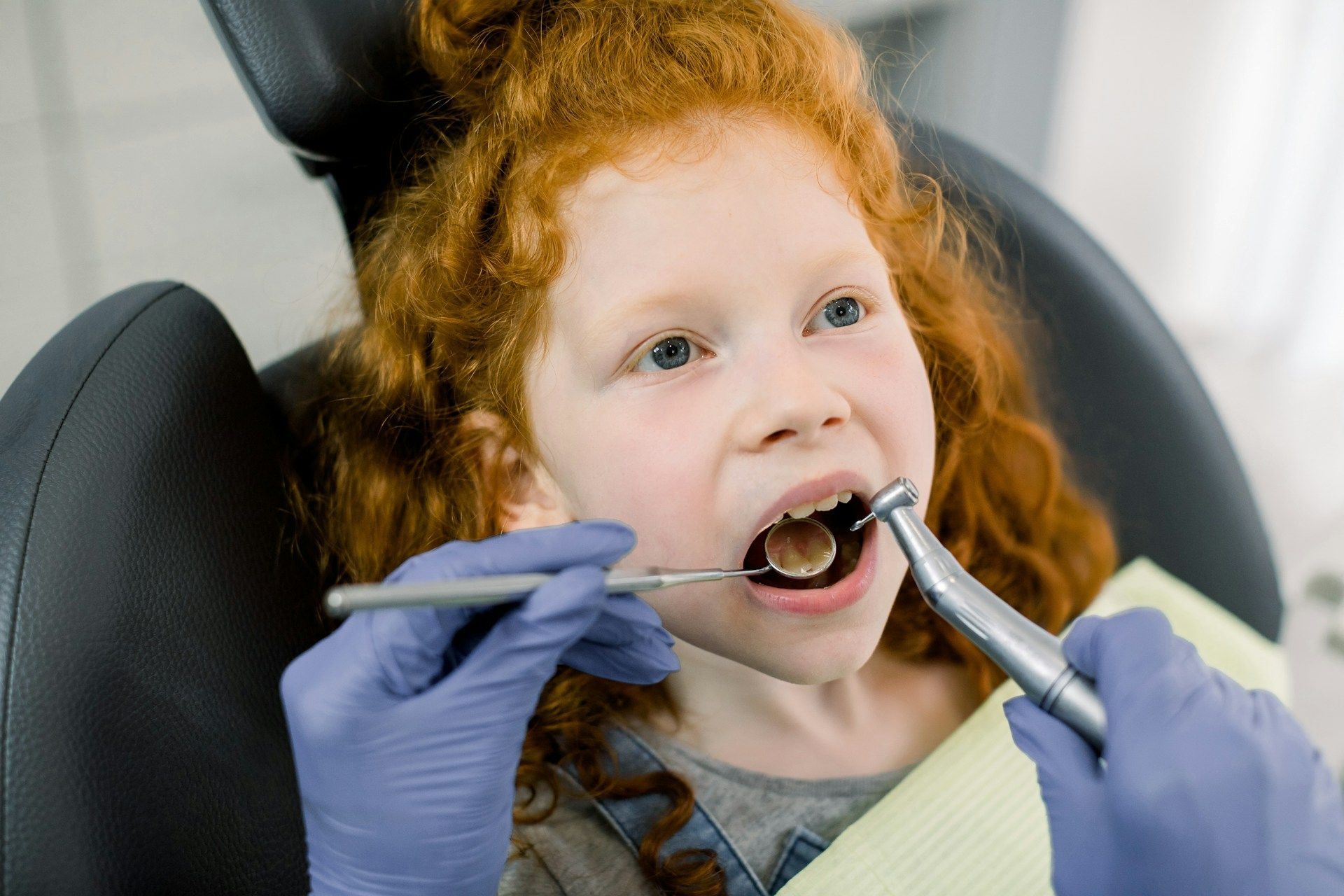 A little girl is getting her teeth examined by a dentist.