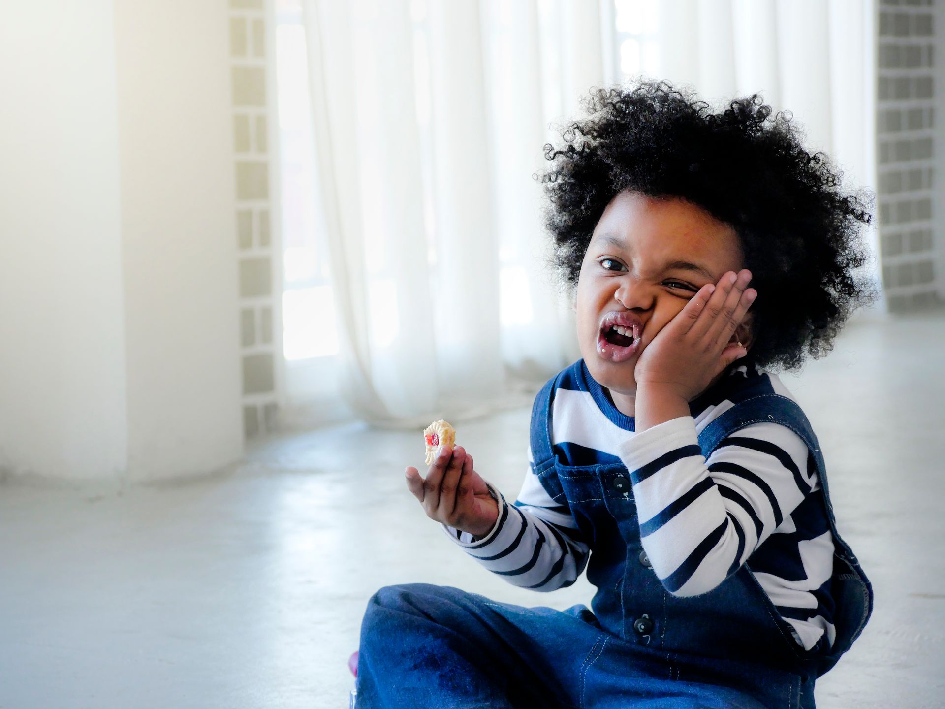 A young boy is sitting on the floor eating an apple.