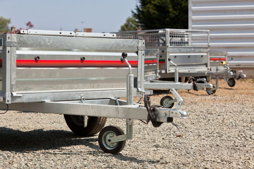 Two Silver Utility Trailers With Red Stripes, Parked on Gravel — Old Mate's Towing Townsville in Deeragun, QLD