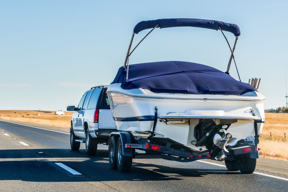 White Suv Towing a Covered White and Blue Motorboat on a Highway — Old Mate's Towing Townsville in Deeragun, QLD