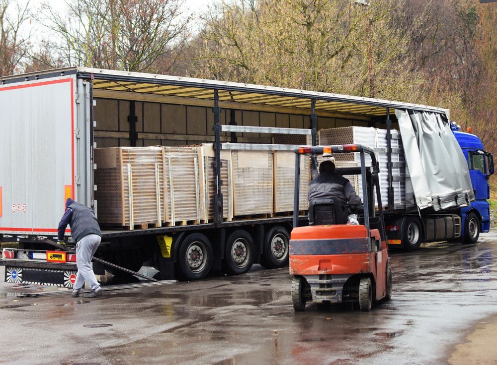 Forklift Loading Wooden Crates Into a Semi-truck Trailer on a Wet — Old Mate's Towing Townsville in Deeragun, QLD