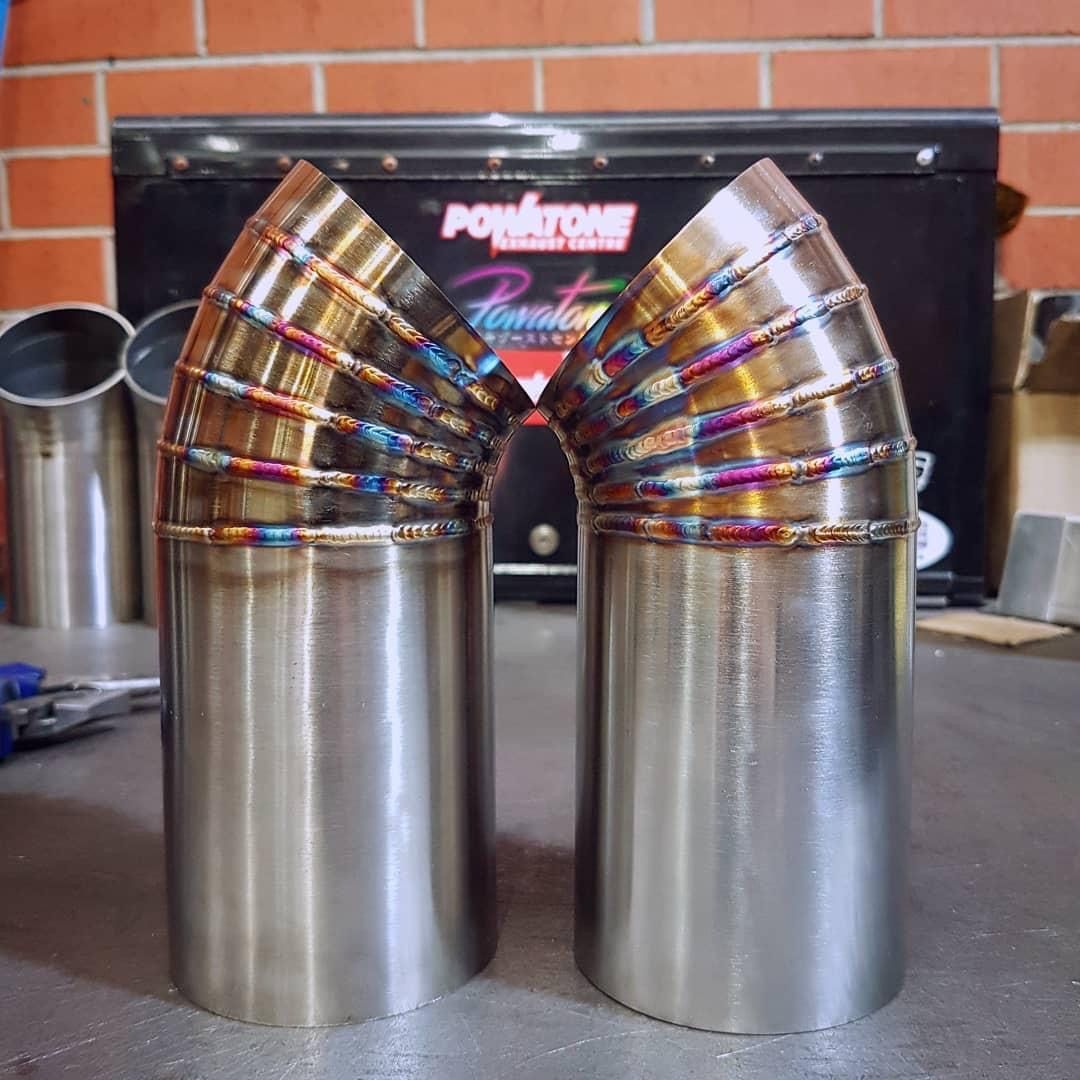 Two Stainless Steel Pipes Are Stacked on Top of Each Other — Powatone Exhaust Centre in Fyshwick, ACT