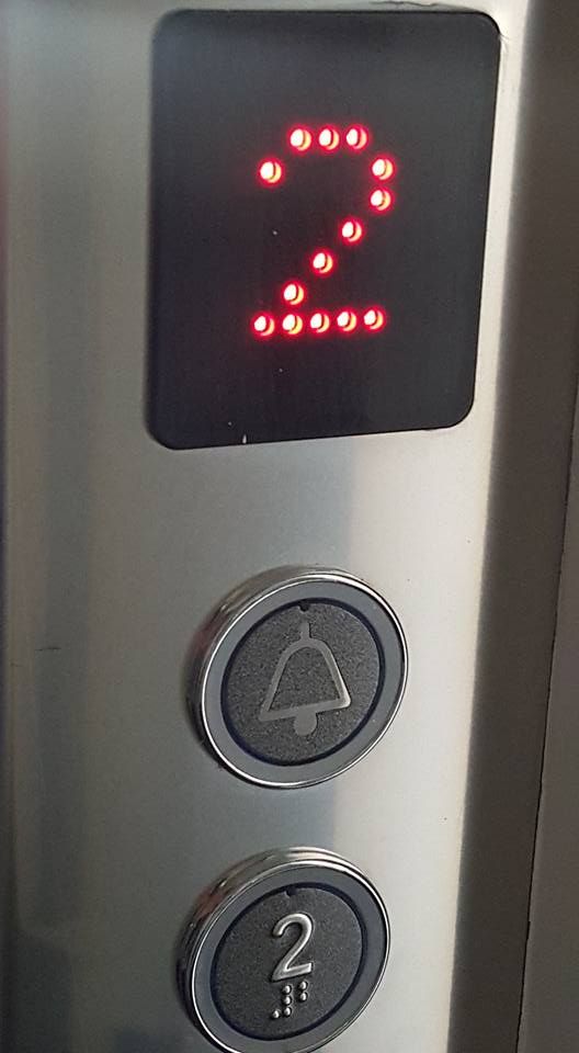 Primo piano del pannello di controllo di un ascensore in acciaio inossidabile con pulsanti e display digitale.